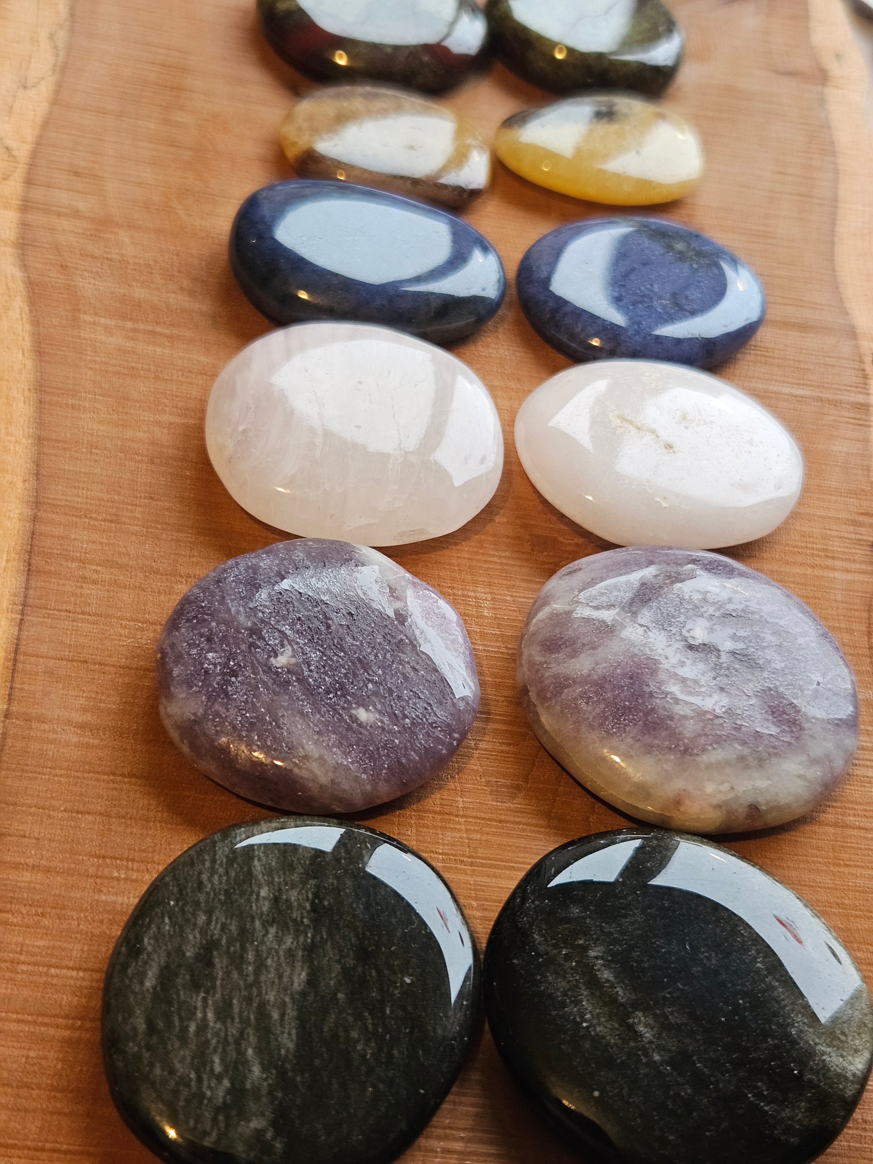 Different coloured gemstone smoothstones on a wooden board