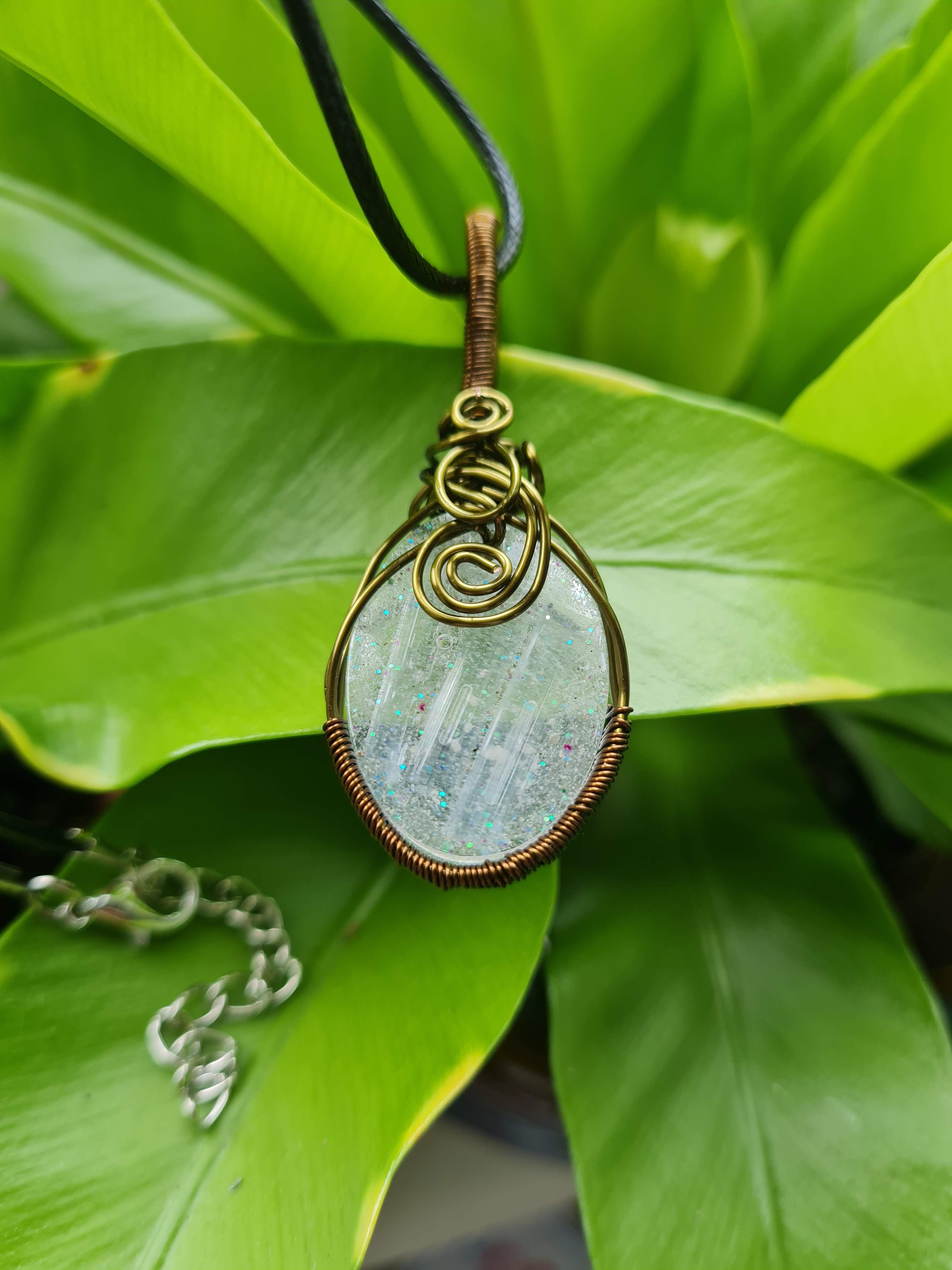 Necklace with a Selenite pendant on a green leaf background