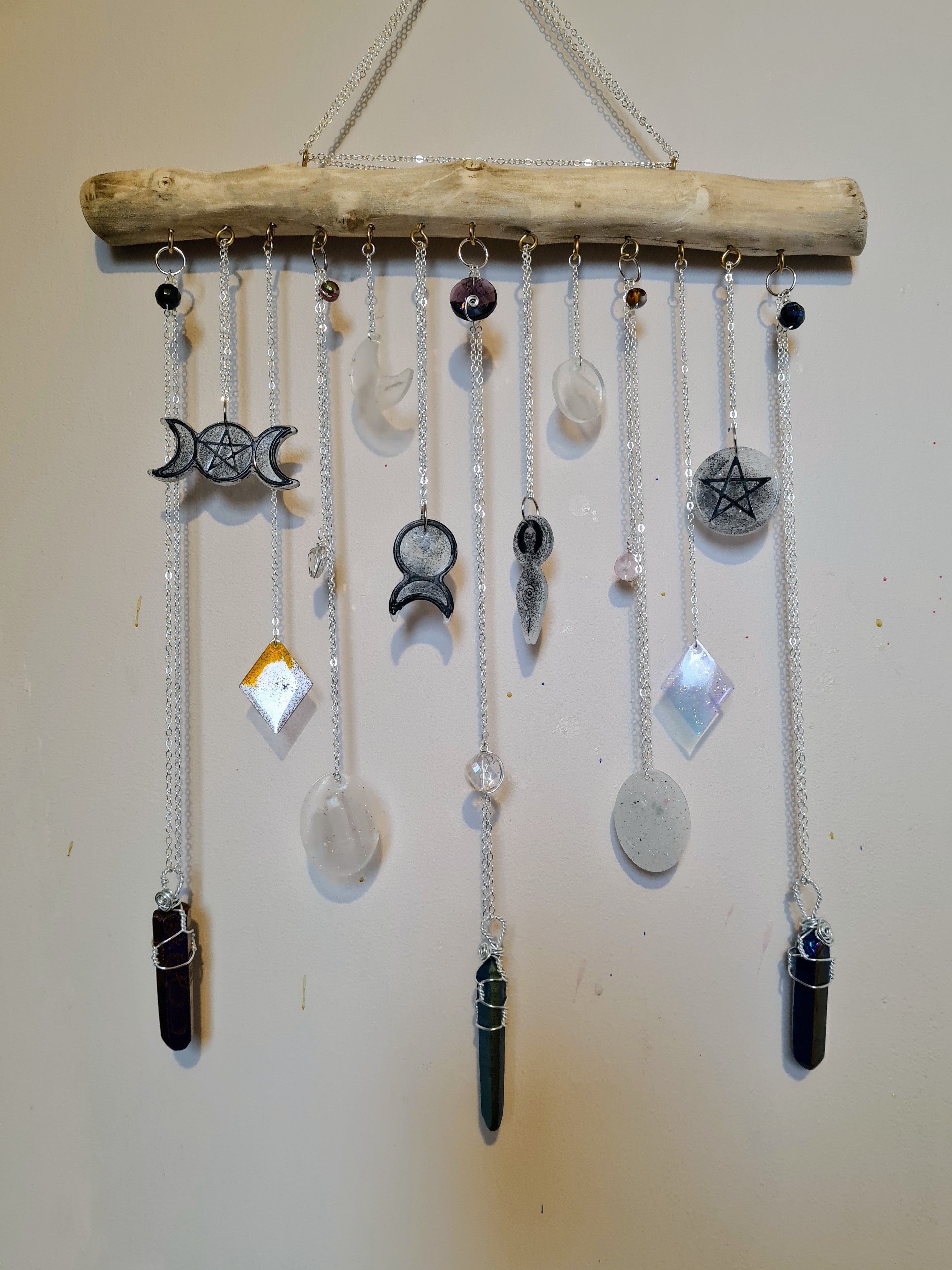 Decorative wall hanging with hanging stones and symbols on a plain background