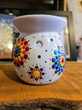 Decorative wax warmer with colorful mandala design on a wooden surface.