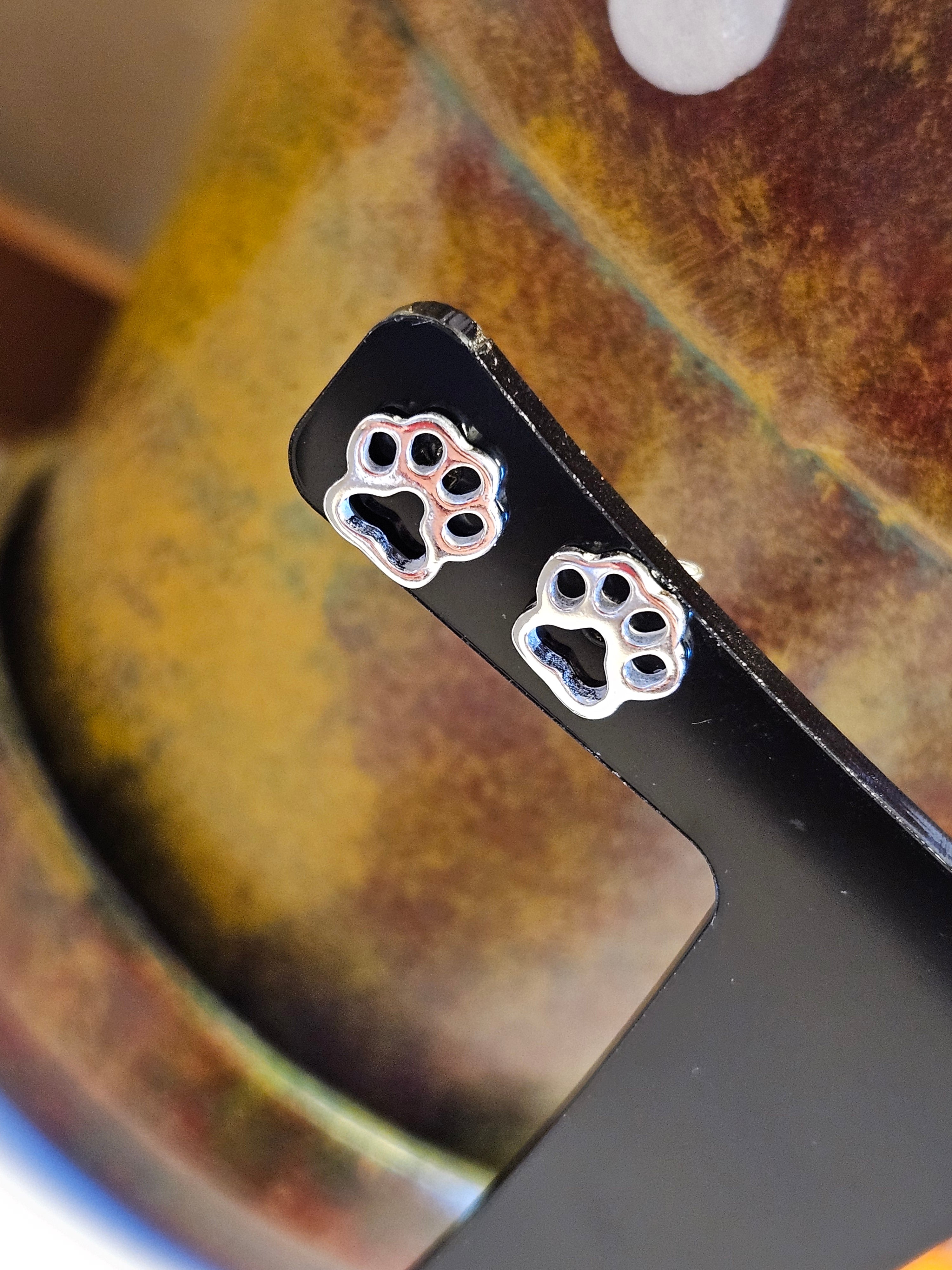 Close up of silver paw print stud earrings