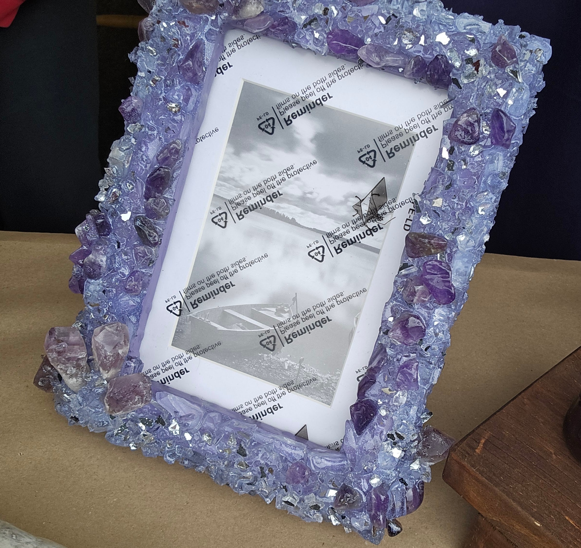 Decorative picture frame with purple Amethyst crystals on a wooden surface