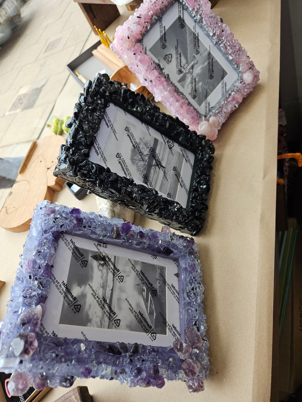 Three decorative picture frames with crystal designs on a wooden surface.