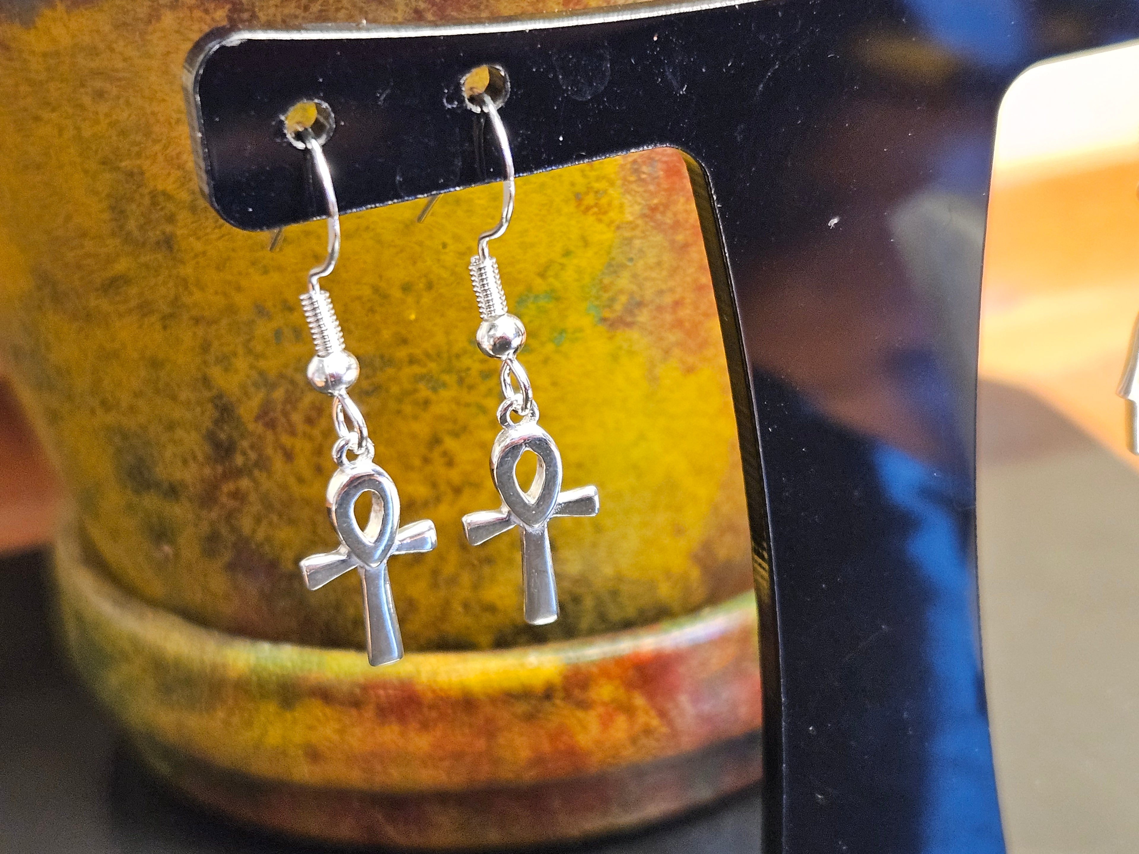Silver Ankh earrings hanging from a black stand