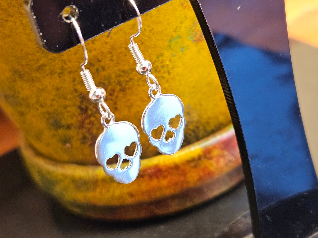 Silver sugar skull earrings on a yellow background