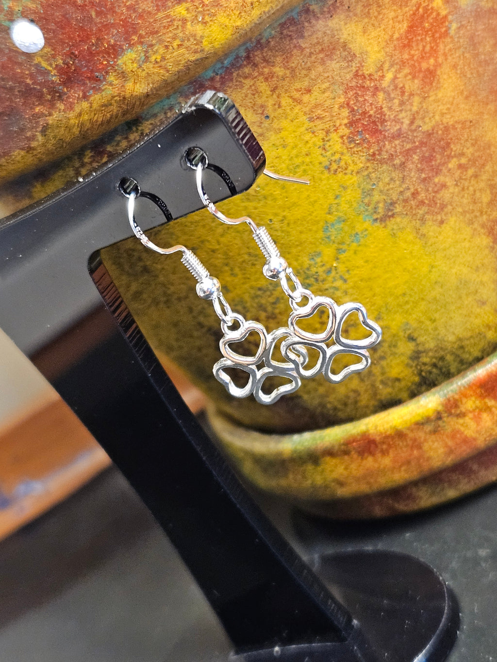 Silver four leaf clover earrings hanging from black stand