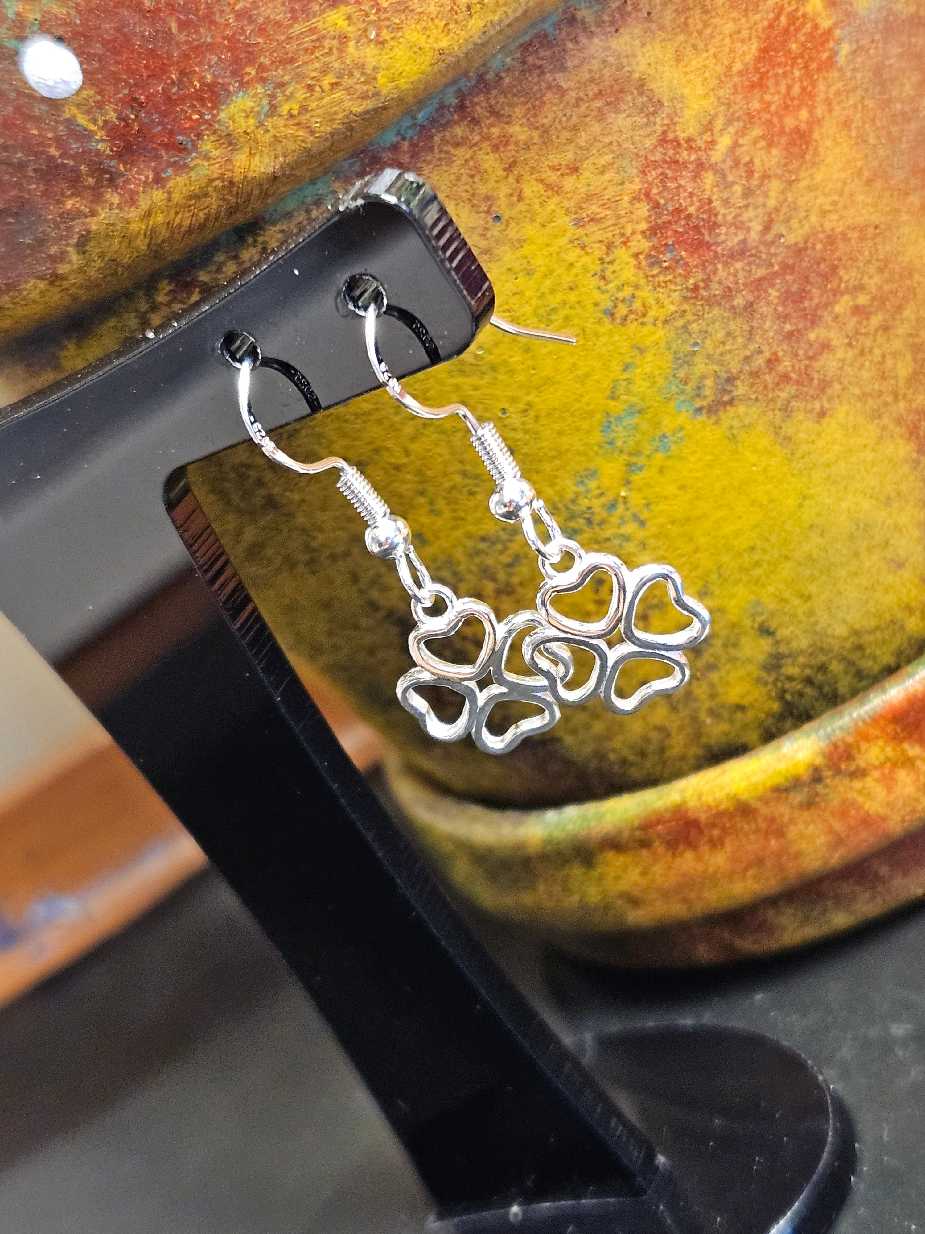 Silver four leaf clover earrings hanging from black stand