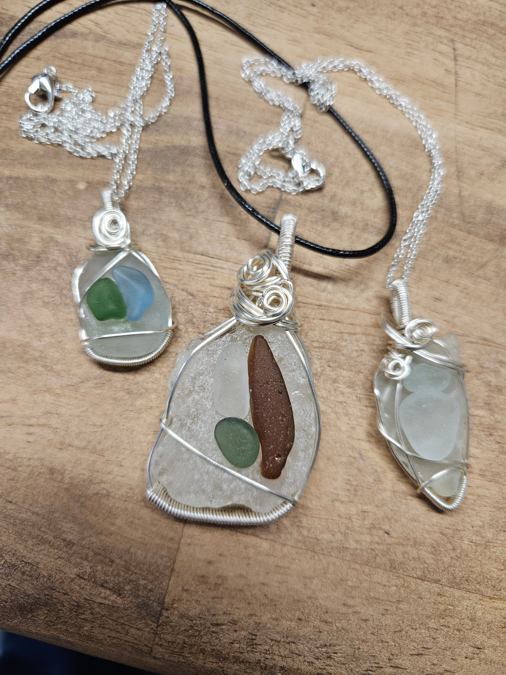 Three Sea glass pendant necklaces on wooden surface