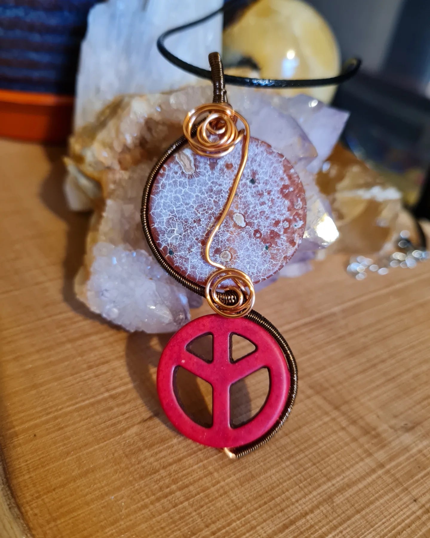 Necklace with a red peace symbol pendant on a wooden surface