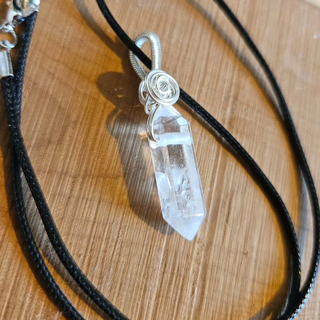 Quartz crystal pendant necklace on a wooden surface