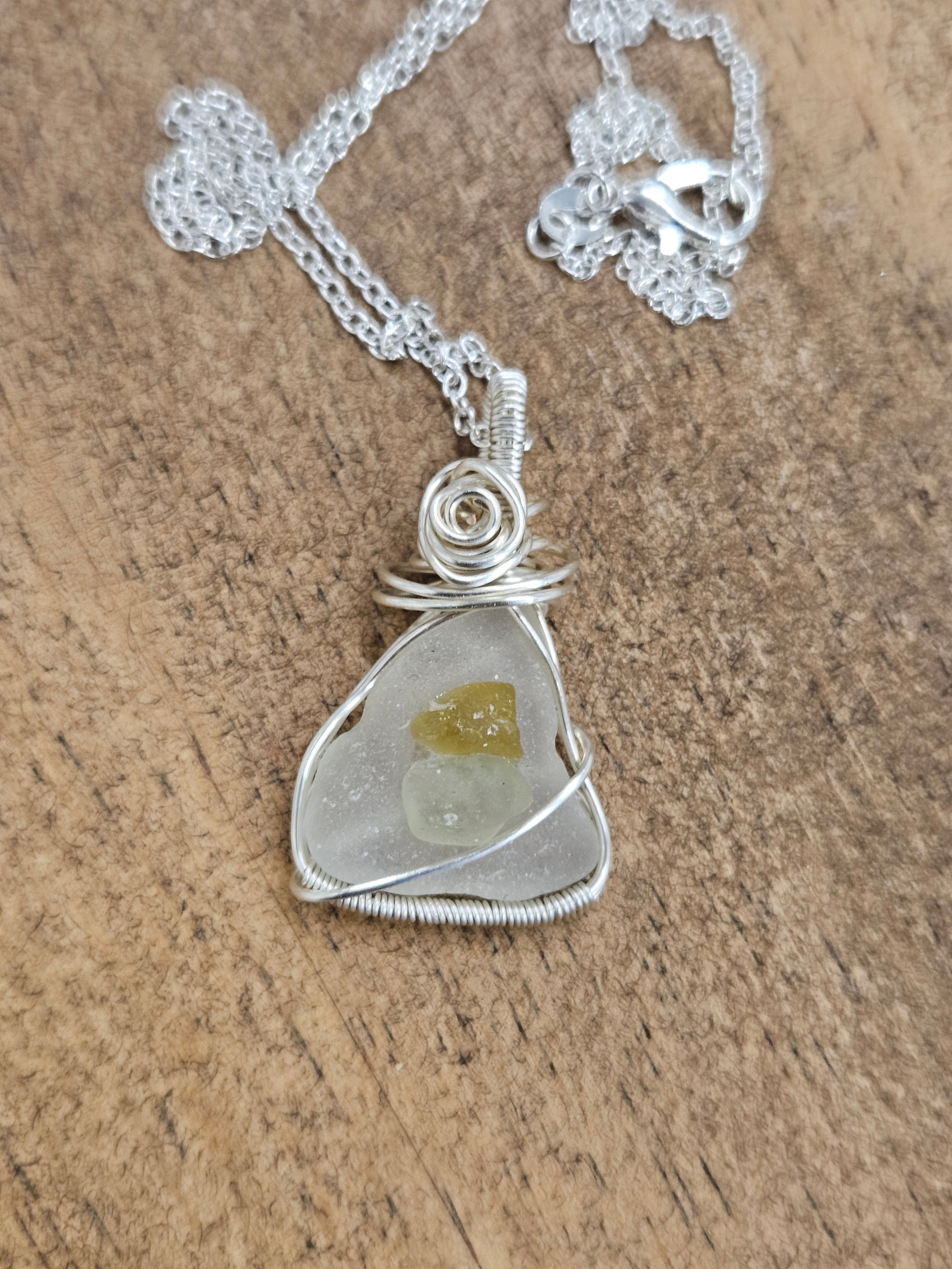 Silver sea glass pendant on a wooden board