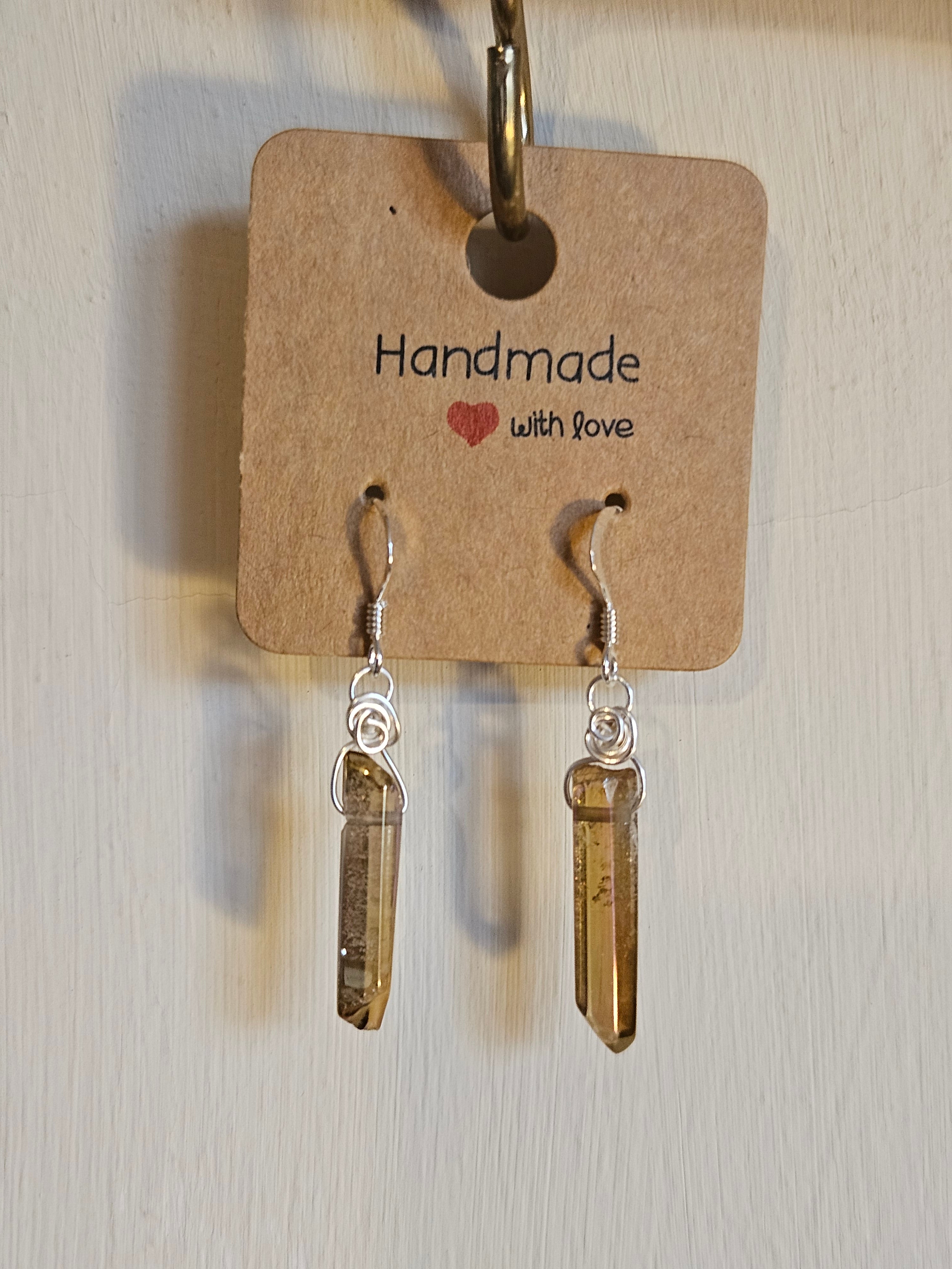 Gold crystal earrings on a 'Handmade with Love' card against a light background