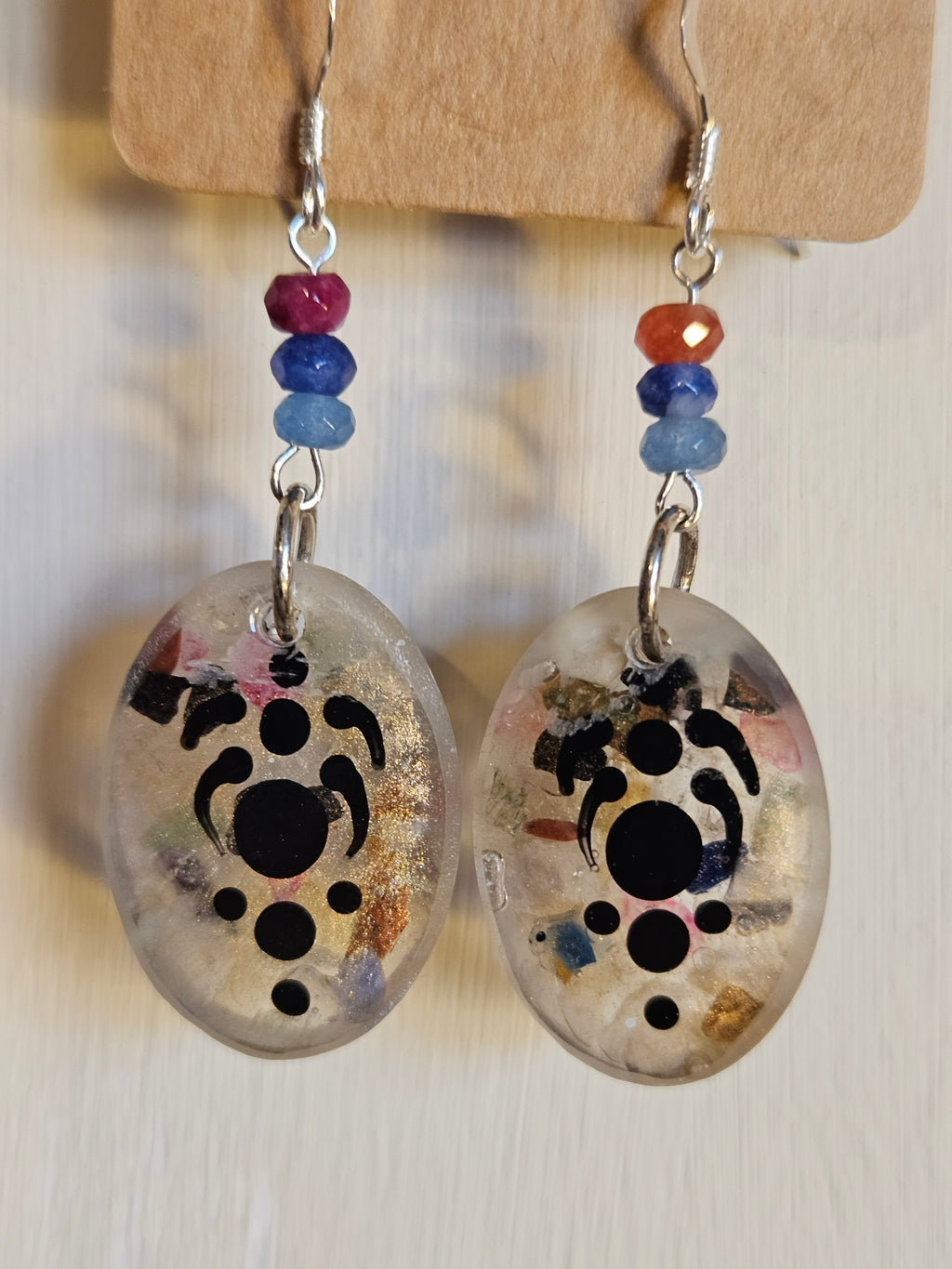 Pair of earrings with abstract print design on a wooden stand.