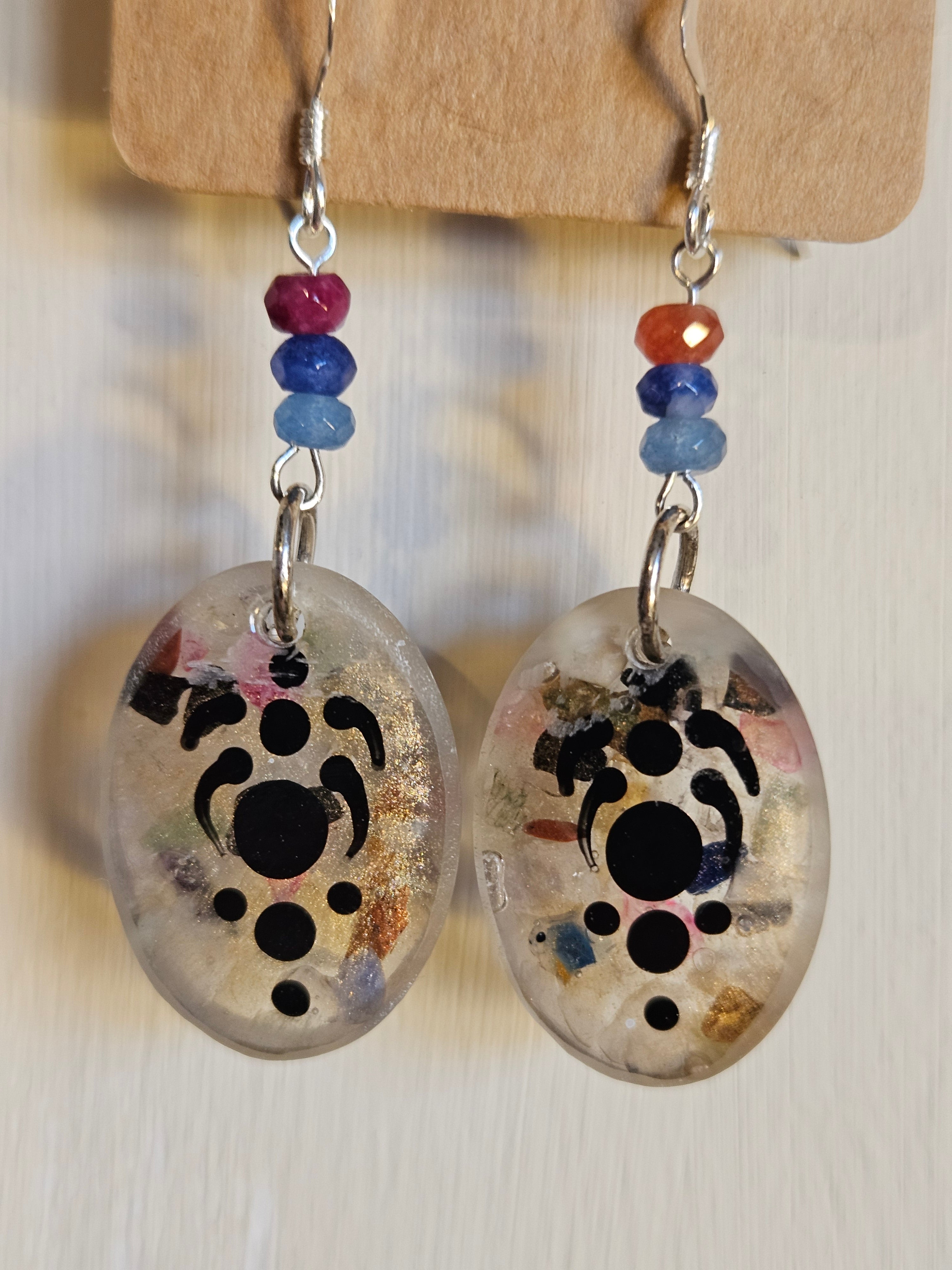 Pair of earrings with abstract print design on a wooden stand.