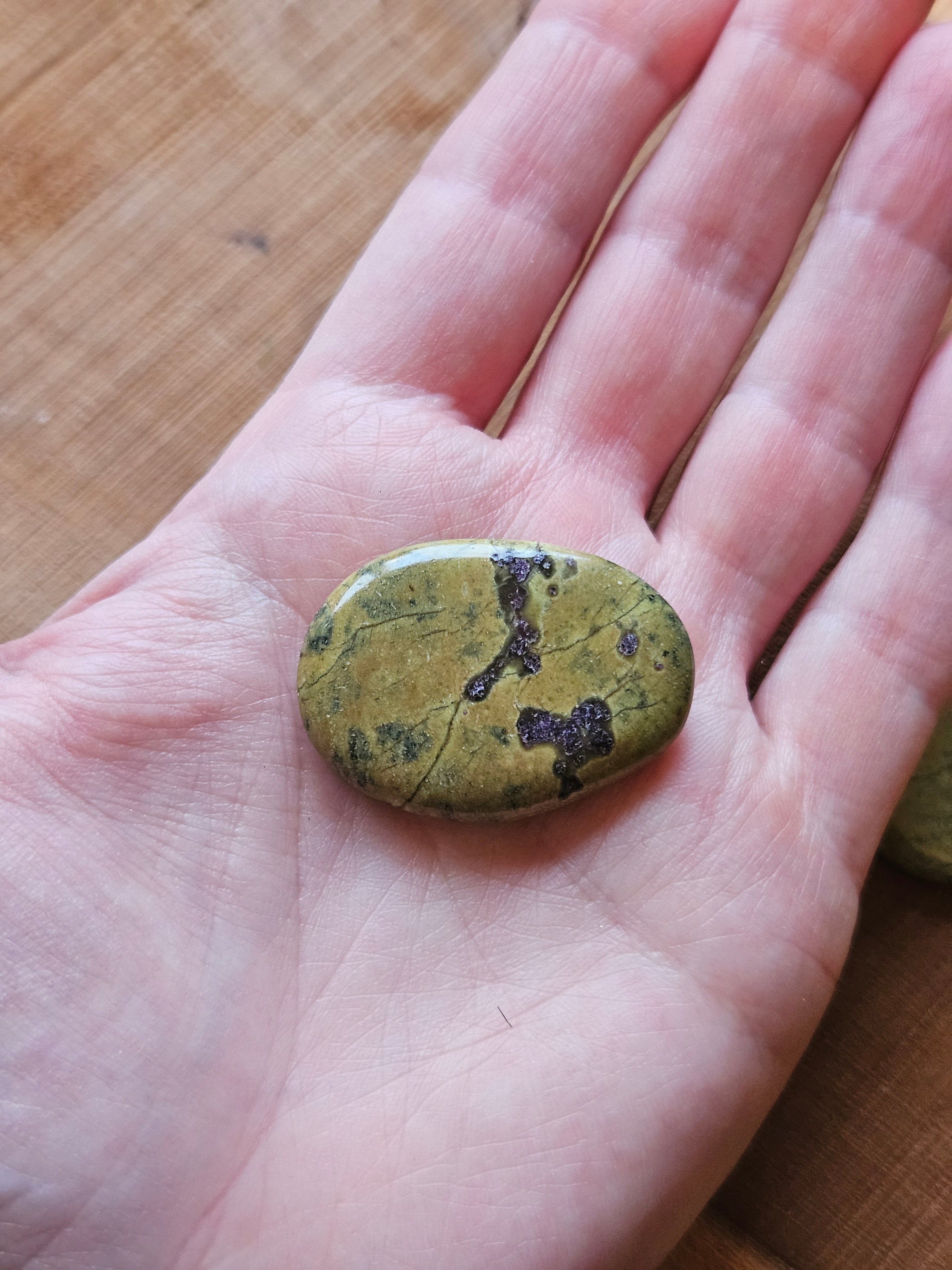 Hand holding Stichtite in Serpentine smoothstone to show size