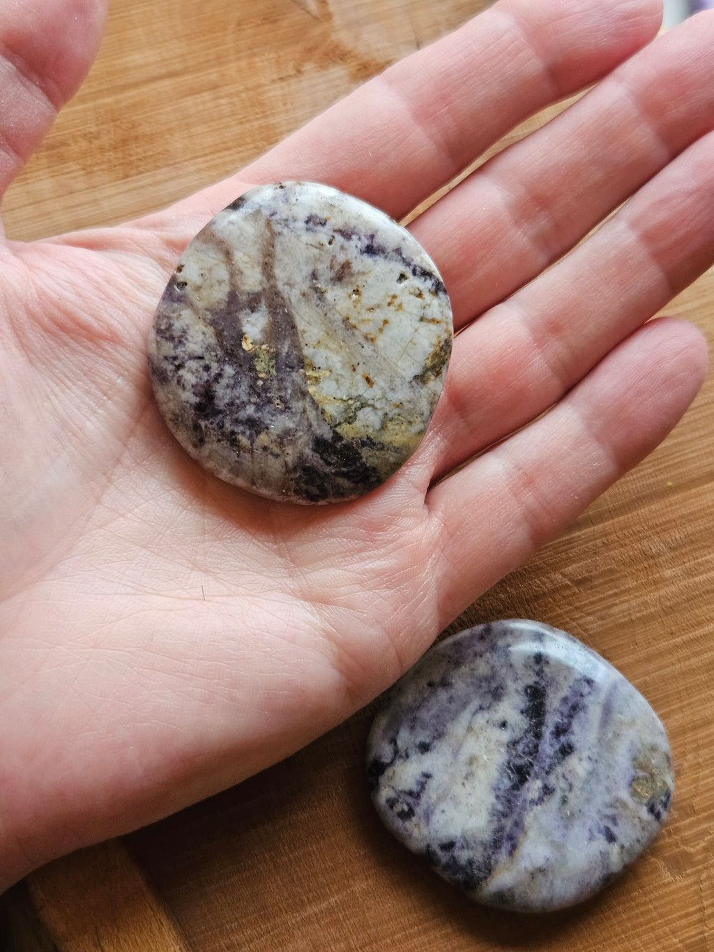 Hand holding a Purple Flower Jasper smoothstone to show size