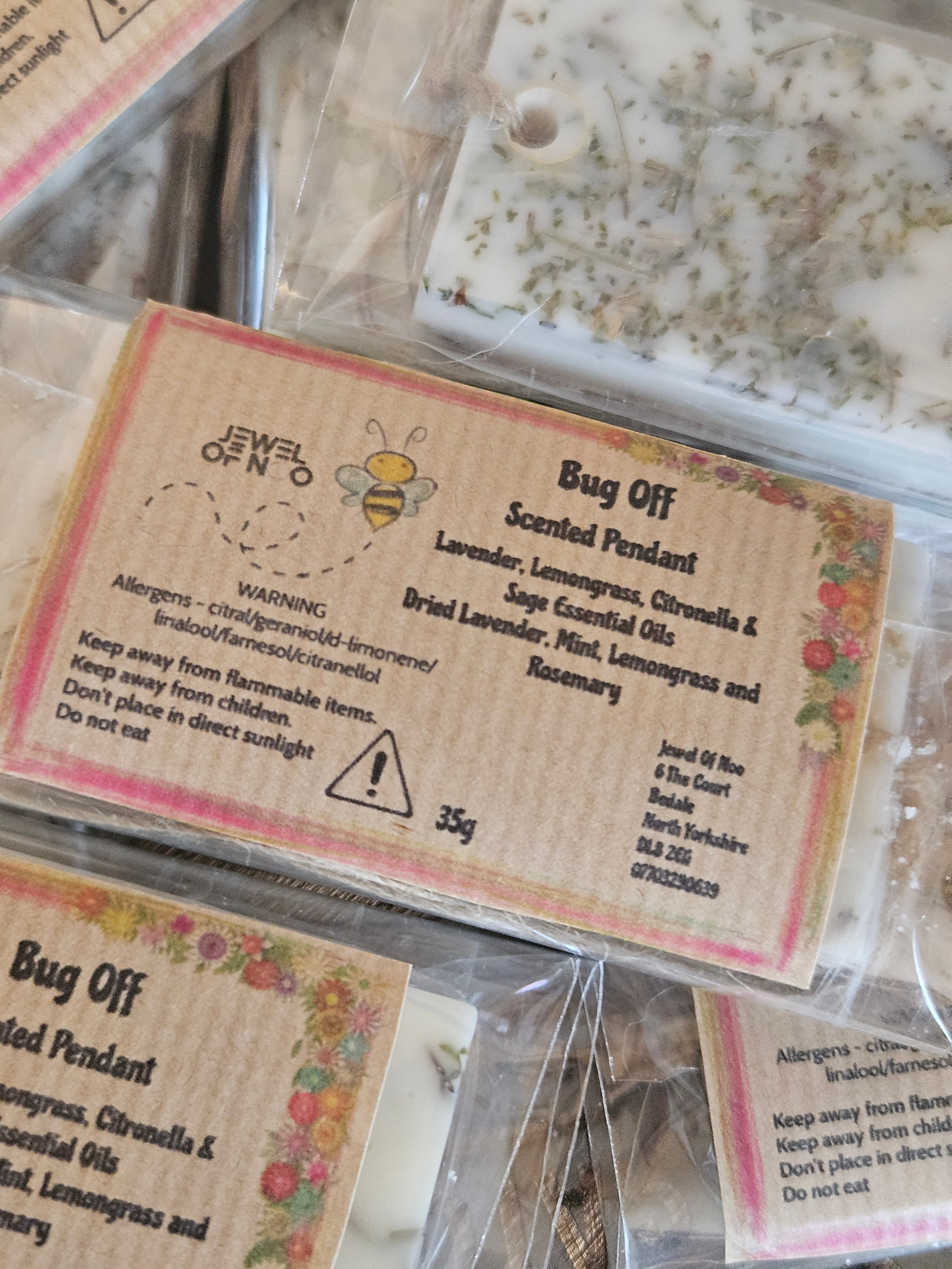 Packaged scented pendants with labels and bee illustrations.