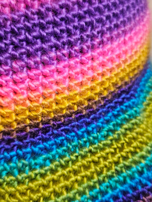 Close-up of a colorful crocheted fabric with a rainbow pattern.