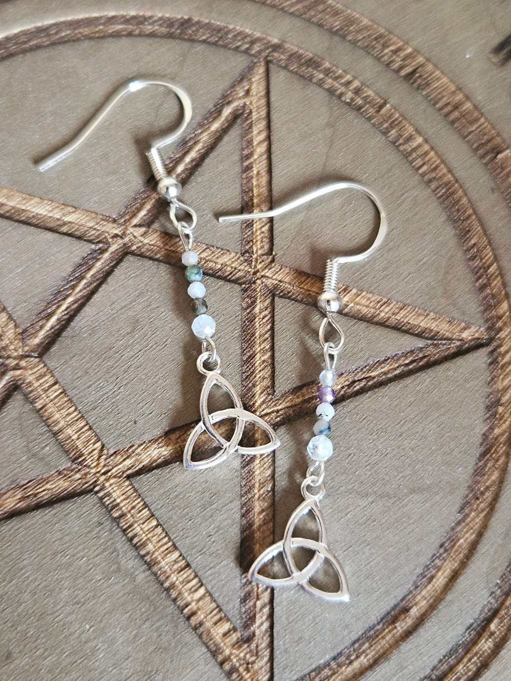 Silver earrings with intricate designs on a wooden surface