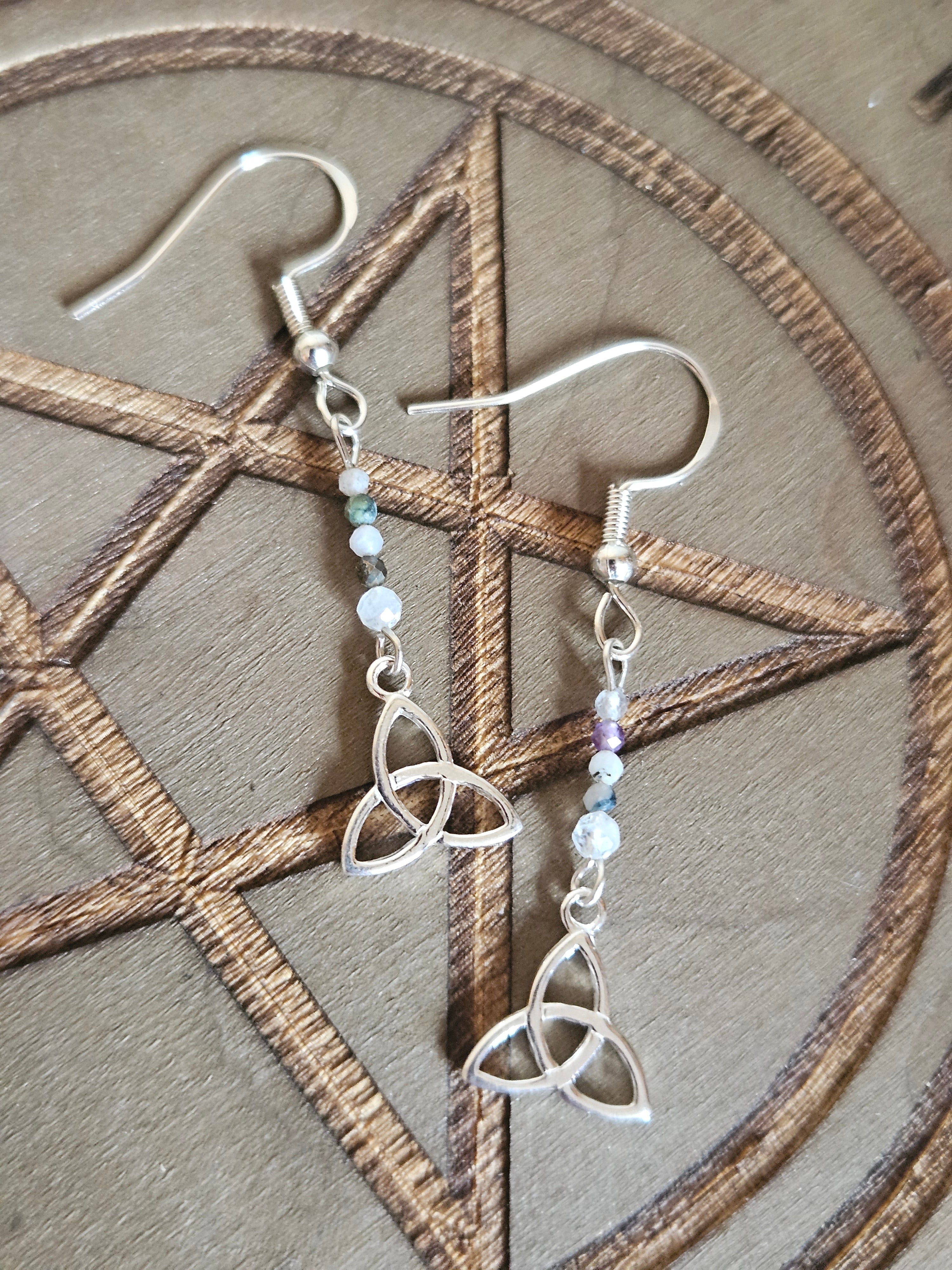 Silver earrings with intricate designs on a wooden surface