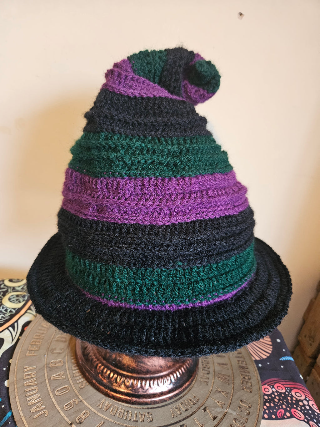 Knitted hat with green and purple stripes on a decorative background