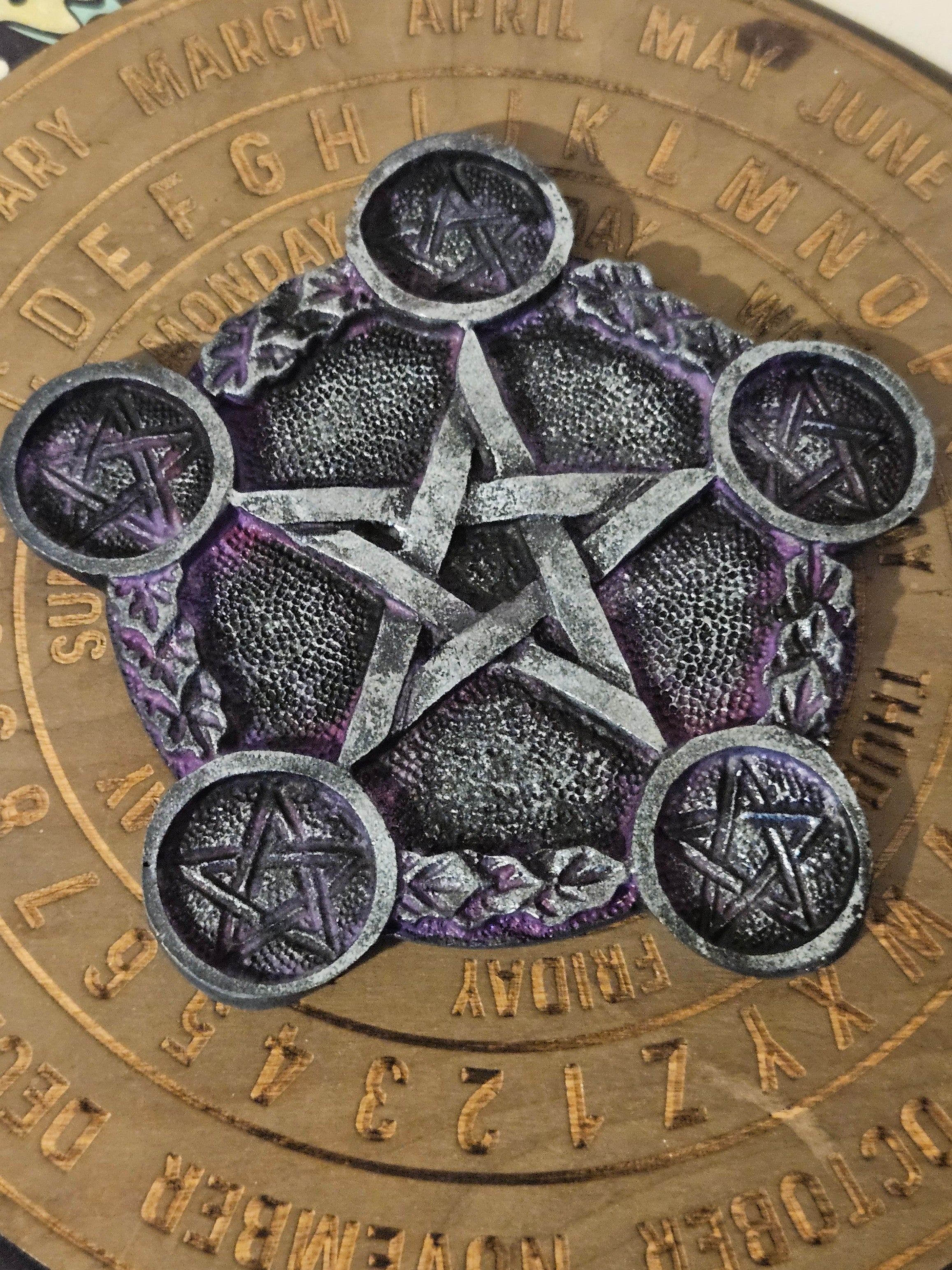 Purple and silver pentagram tea light holder on a wooden board