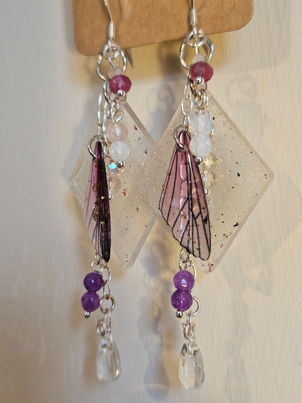 Handmade jewelry with purple and clear beads on a wooden stand.