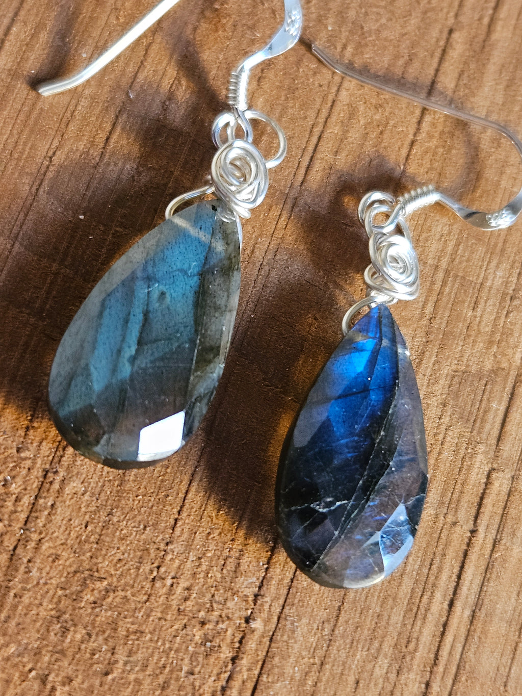 Pair of Labradorite teardrop earrings on a wooden surface