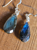 Pair of Labradorite teardrop earrings on a wooden surface