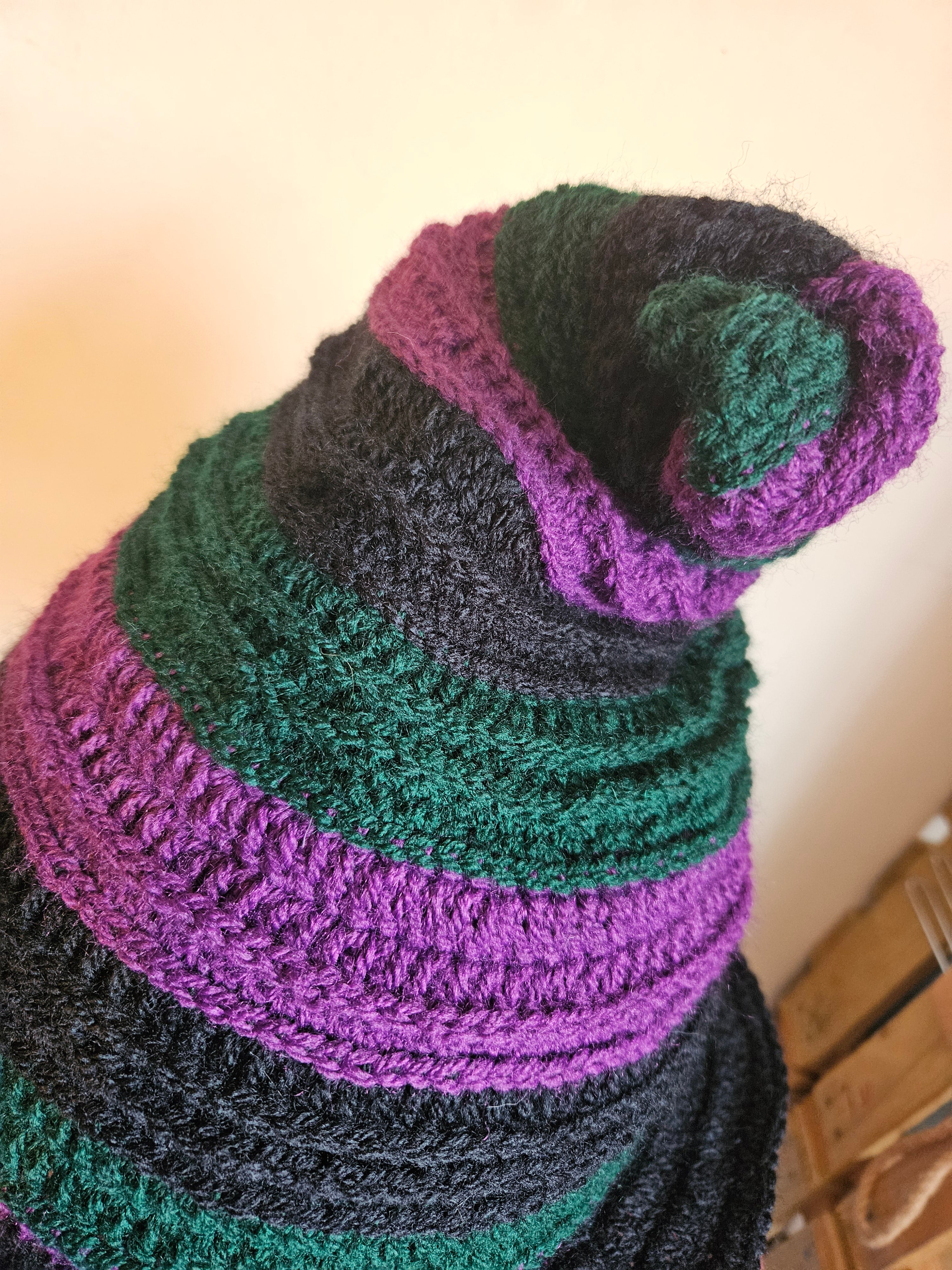 Crocheted hat with purple and green pattern on a neutral background