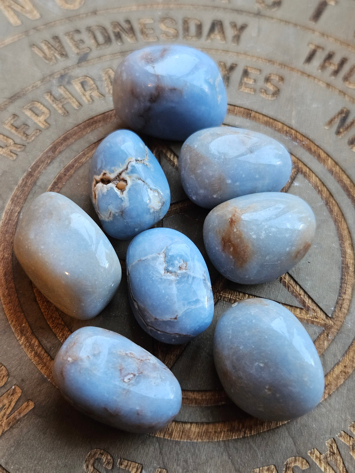 Blue Angelite tumble stones on a wooden board