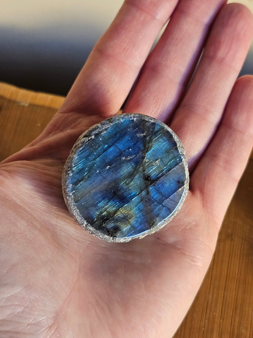 Hand holding a blue labradorite stone to show the size