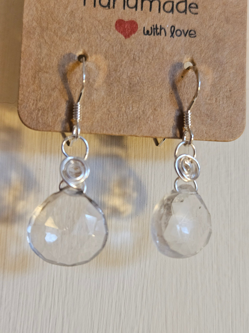 Clear teardrop earrings on a 'Handmade with Love' card against a light background