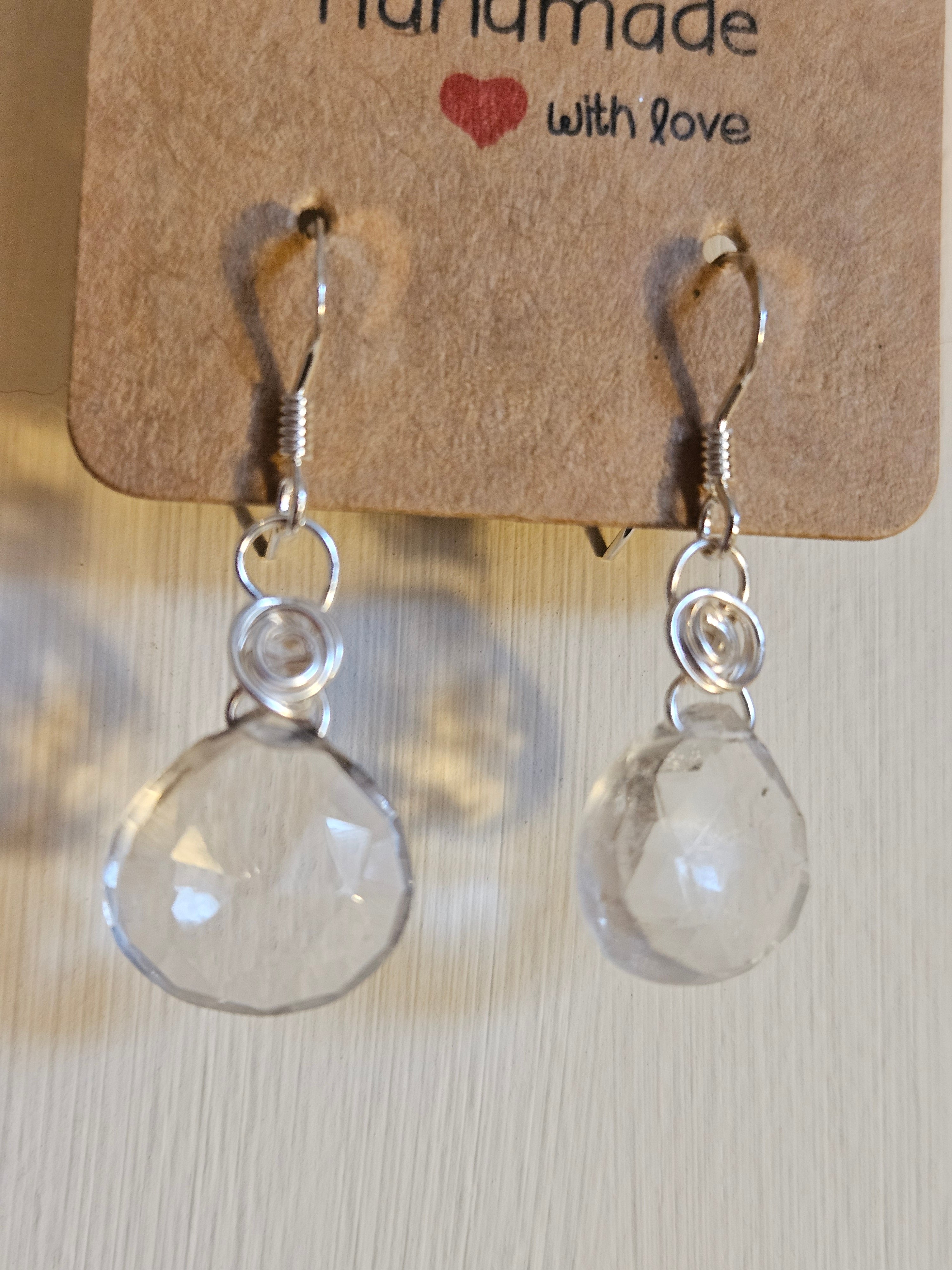 Clear teardrop earrings on a 'Handmade with Love' card against a light background