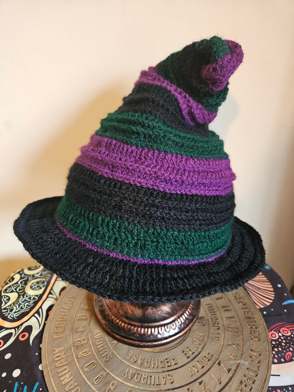 Crocheted hat with green and purple stripes on a decorative object