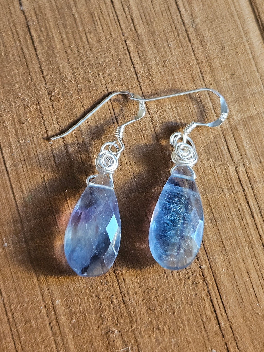 Teardrop-shaped blue/green/purple earrings on a wooden surface