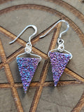 A pair of handmade triangular dangle earrings with sterling silver wire hooks, featuring a purple drusy Quartz displayed on a wooden background with a pentagram design.