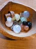 Set of colorful stone mushrooms in a wooden bowl on a wooden surface