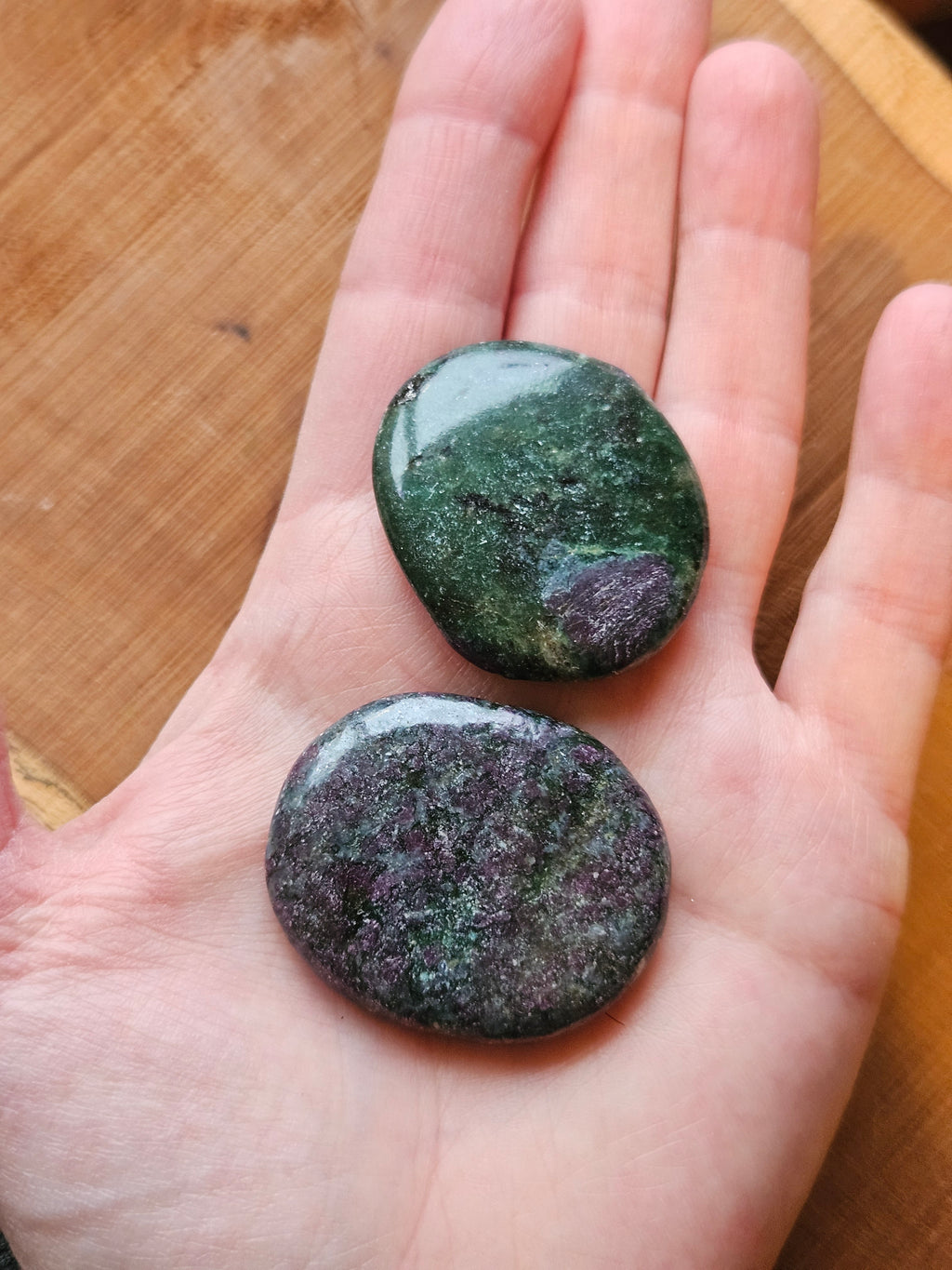 Hand holding two Ruby in Fuchsite smoothstones to show size