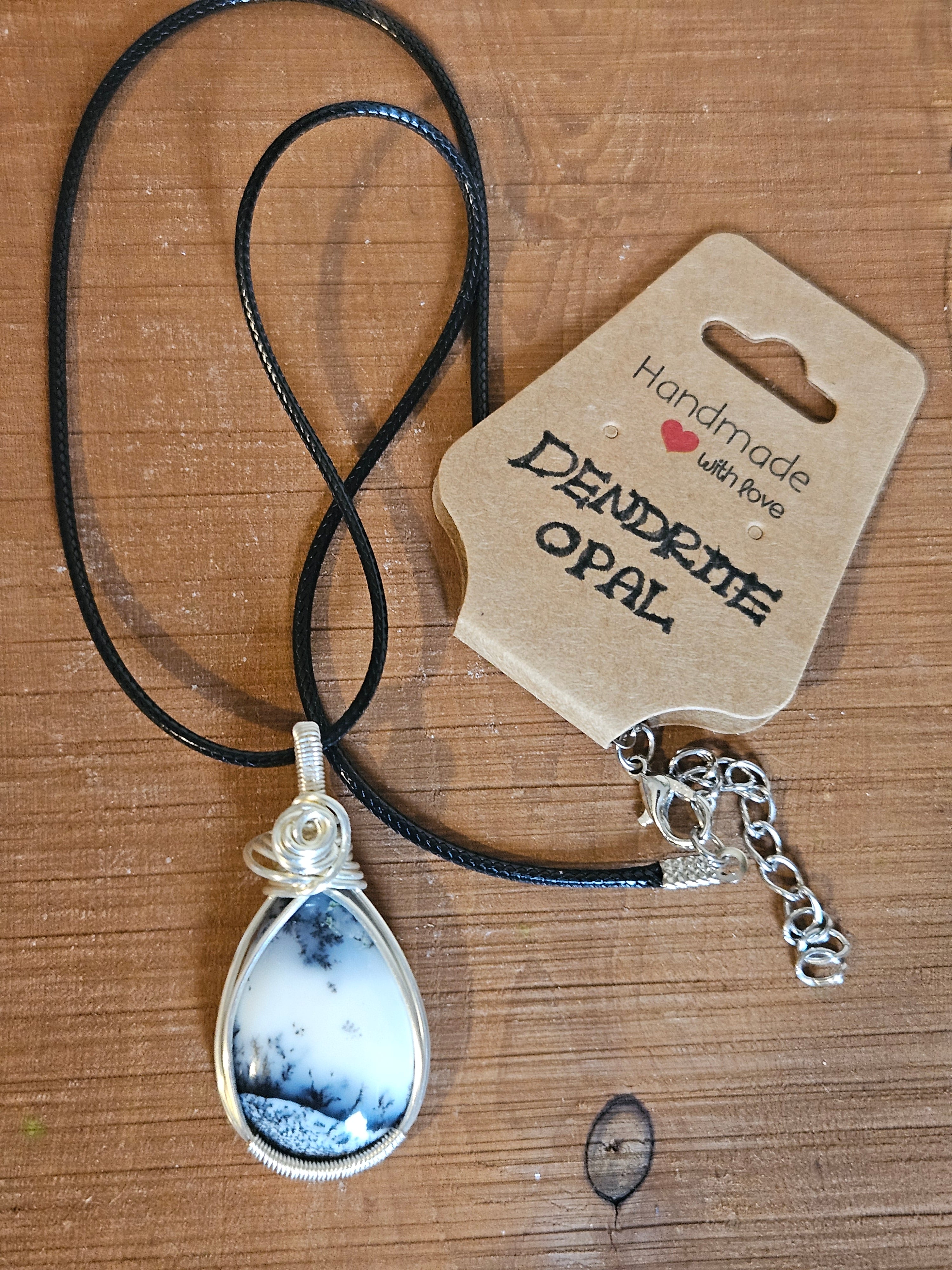 Necklace with dendritic opal pendant on a wooden surface, featuring a 'Handmade with Love' tag.