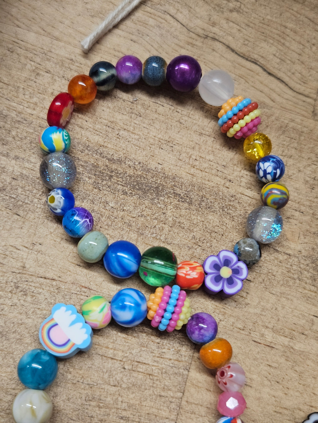 Colorful beaded bracelet with various shapes and patterns on a wooden surface