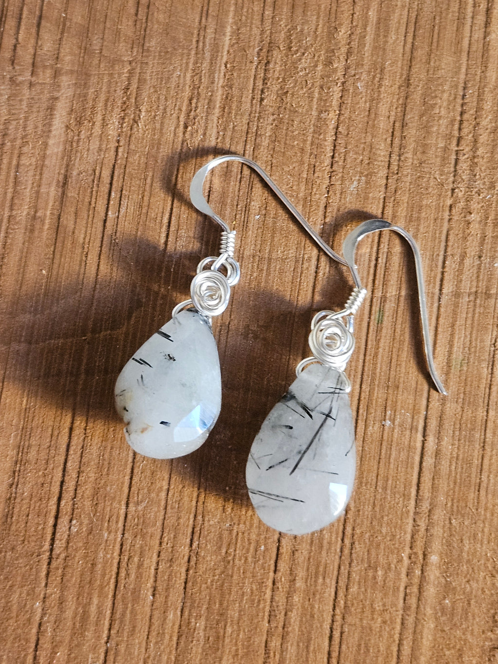 Pair of earrings with teardrop-shaped gemstones on a wooden surface