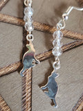 Silver cat-shaped earrings on a wooden surface