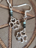 Silver four-leaf clover earrings with green beads on a wooden surface