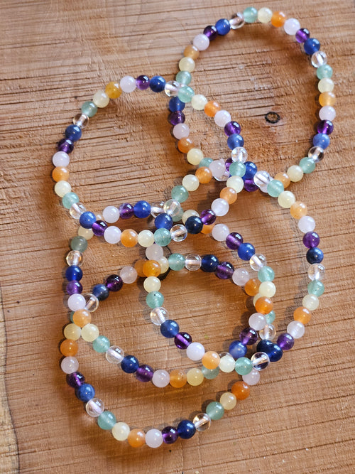 Set of colorful beaded chakra bracelets on a wooden surface