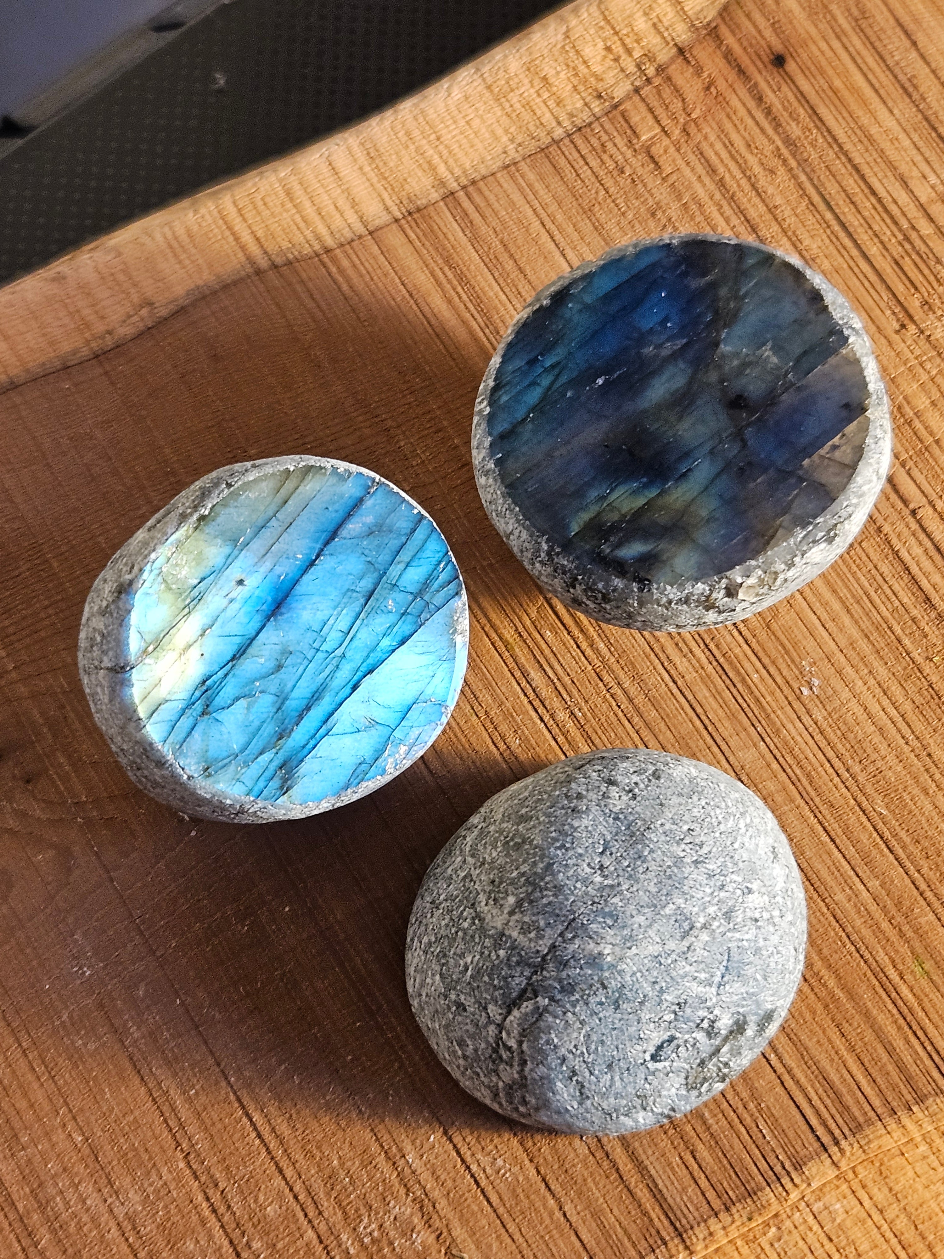 Three polished labradorite stones on a wooden surface