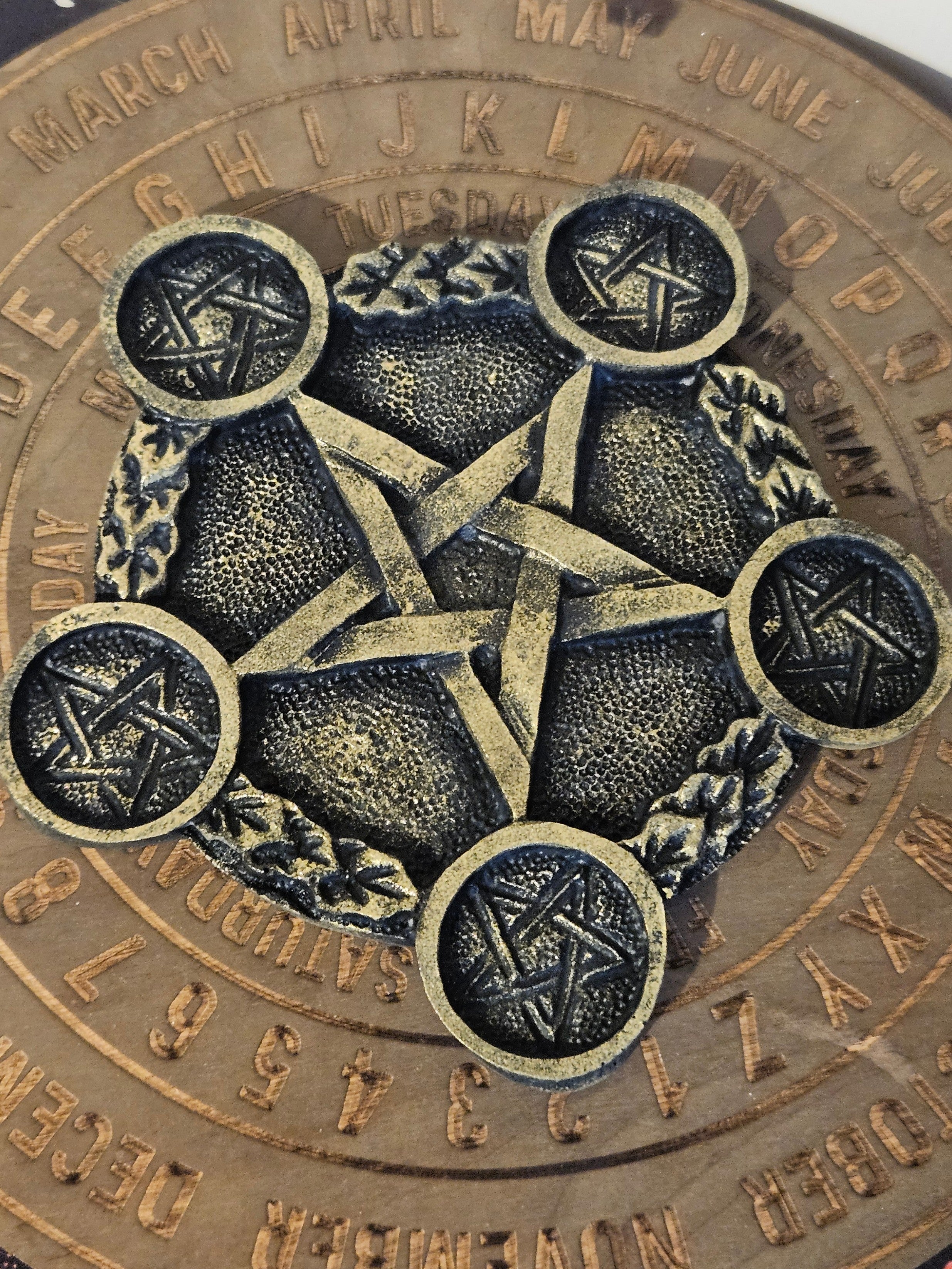 Black and gold pentagram tea light holder on a wooden board