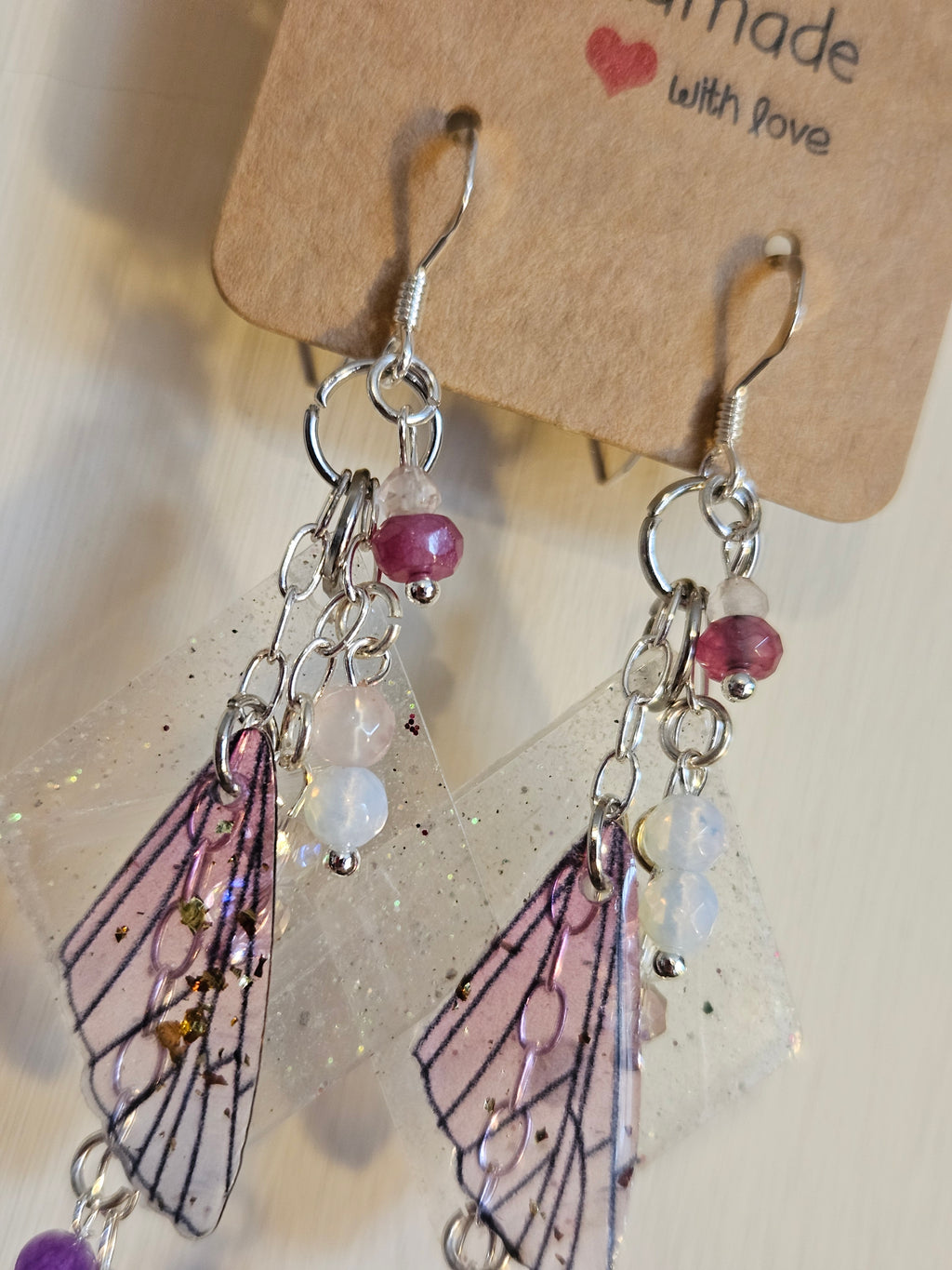 Earrings with pink gemstones and butterfly wings on a white background