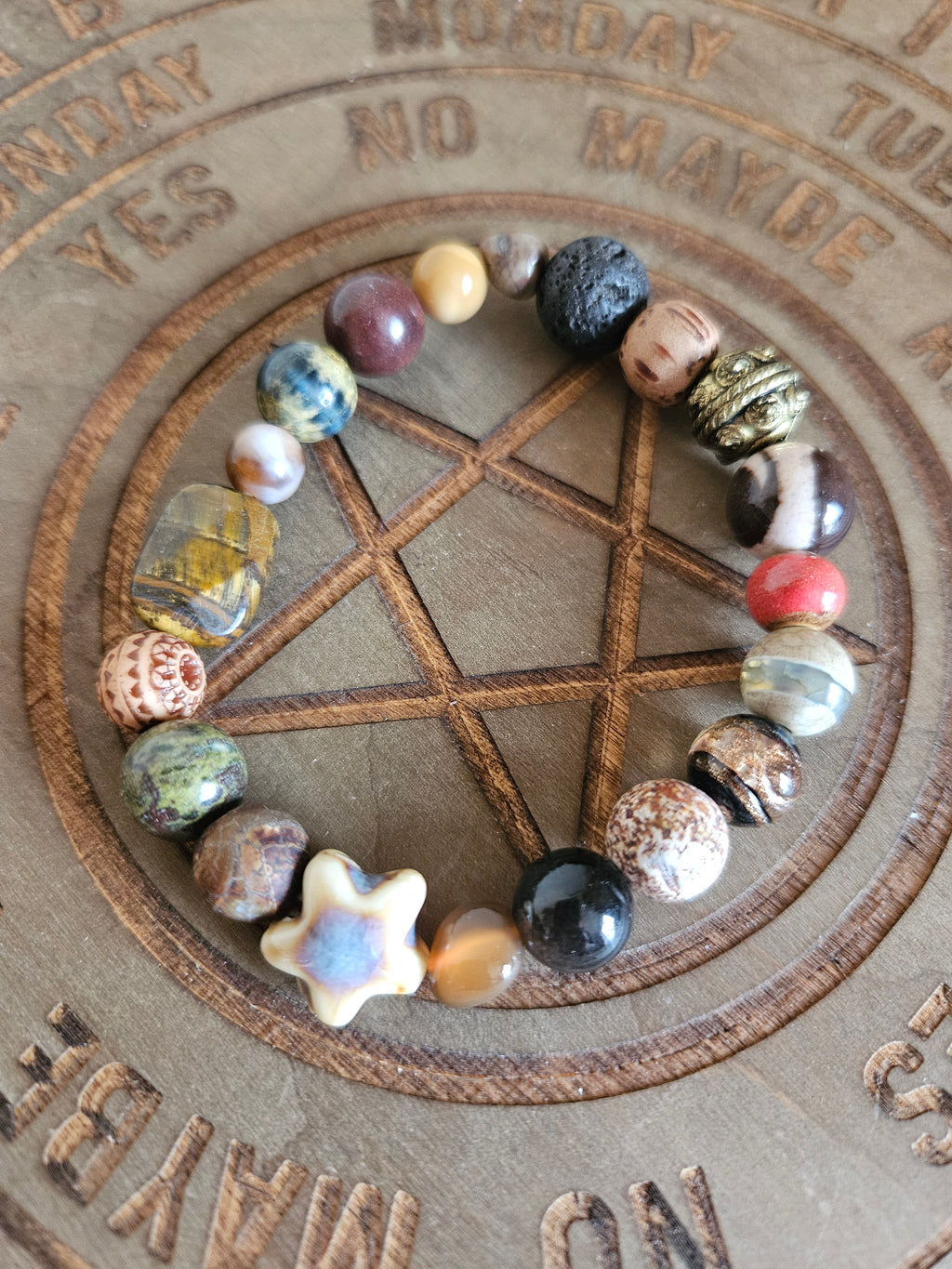 Beaded boho bracelet in warm tones on a wooden pentagram board