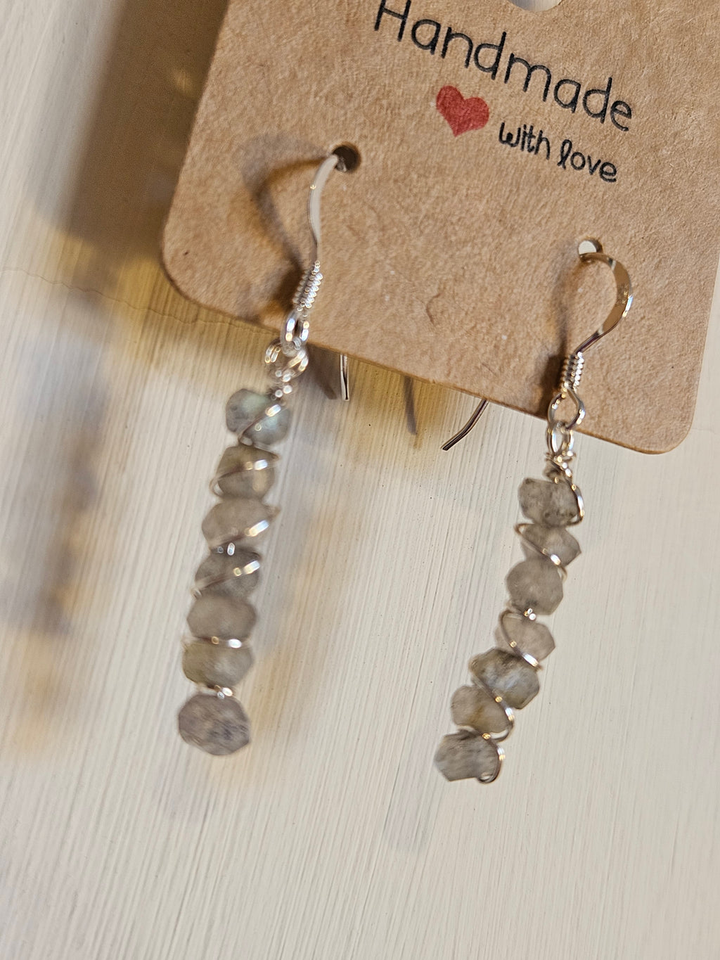 Handmade jewelry with a 'Handmade with Love' tag on a wooden surface